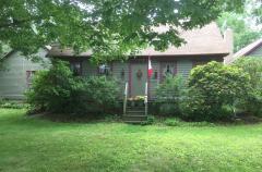 Rustic house with a Canadian flag and lush garden.