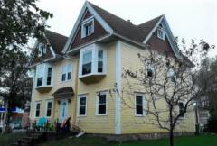 Yellow two-storey house with bay windows and triangular gables.